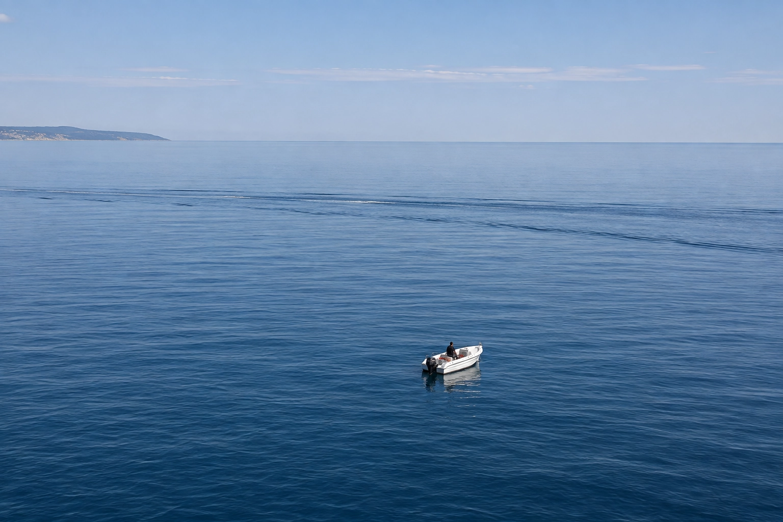 Piccola barca a motore lontana dalla costa, trascinata al largo mentre un uomo cerca di governarla con una pagaia
