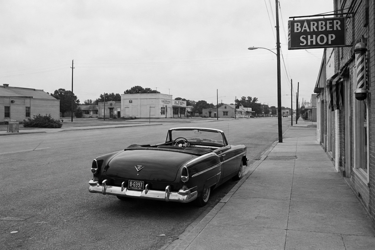 Automobile cabriolet d’epoca parcheggiata davanti a un barber shop in una strada americana deserta