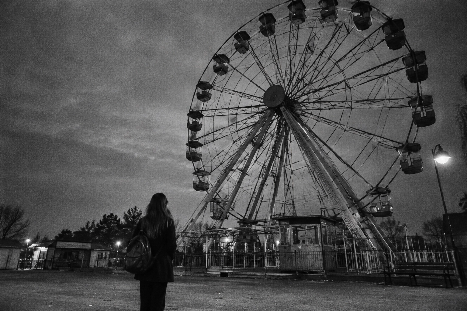 Ragazza davanti a una ruota panoramica in un luna park abbandonato
